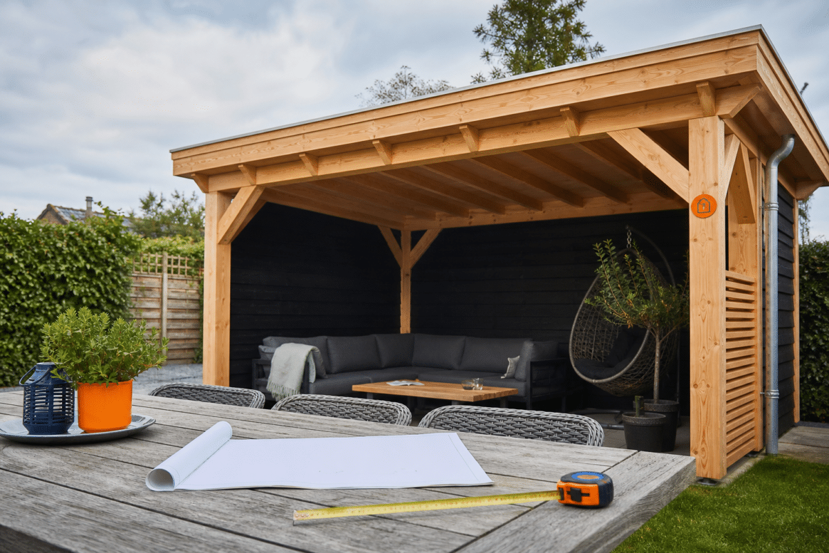 Afgewerkte maatwerk houten overkapping van douglas hout met loungehoek in een Nederlandse tuin