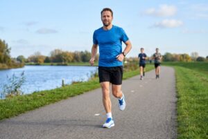 Hardloper op een rustige duurloop over een fietspad langs de rivier in de Nike Vomero Plus, met twee lopers verderop