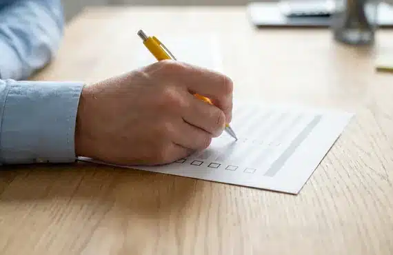 Hand zet met een gele pen vinkjes op een controlelijst